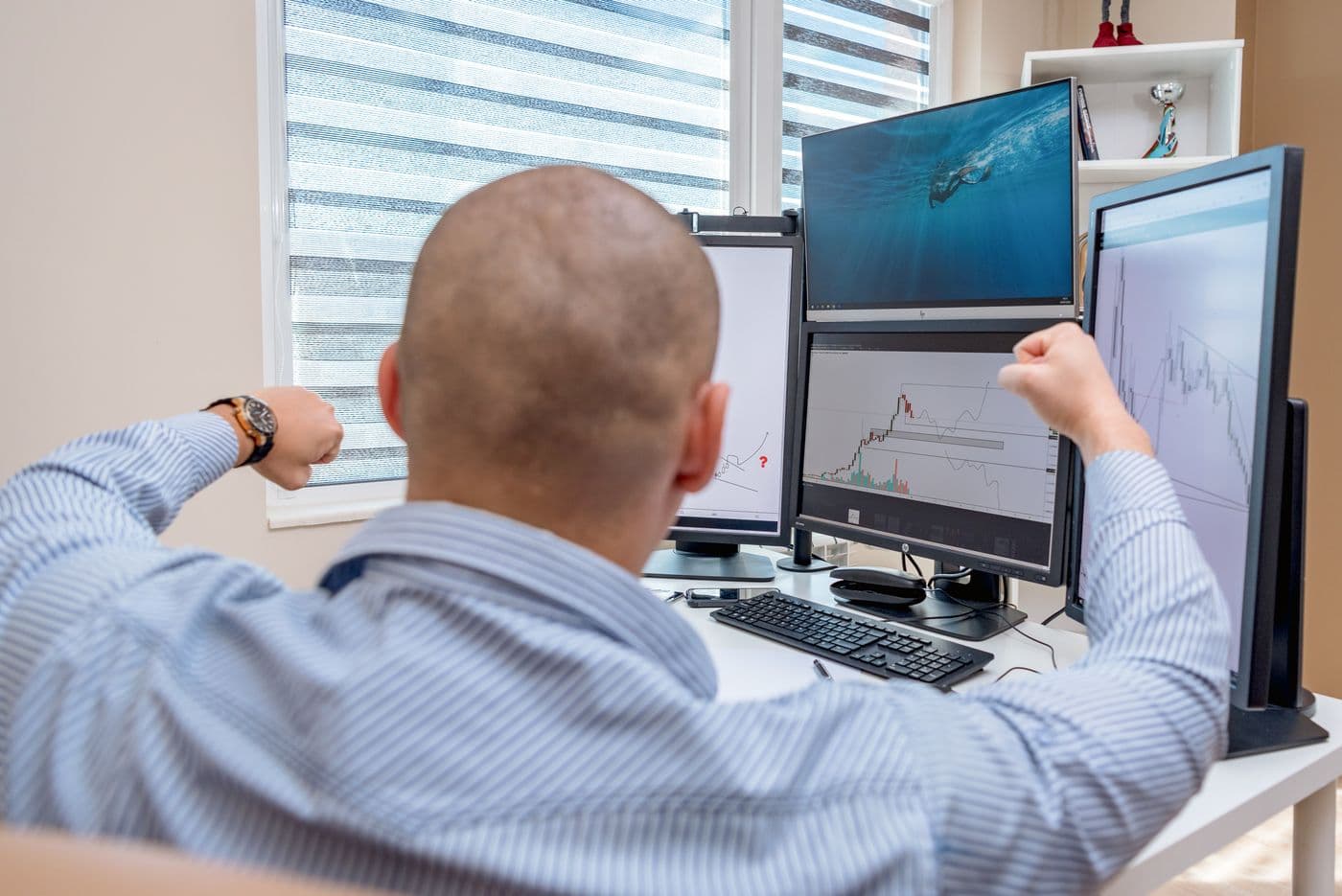 A funded futures trader at a multi-monitor desk watching live charts